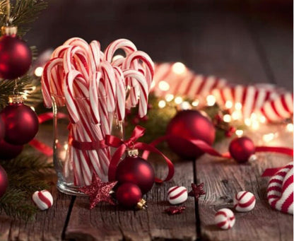 Candy canes in a jar. Ornaments, lights & peppermints scattered around the surface.